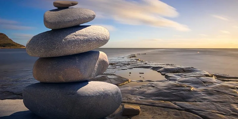 Stacked stones at the water's edge — Dr Vin's stress and resilience workshops